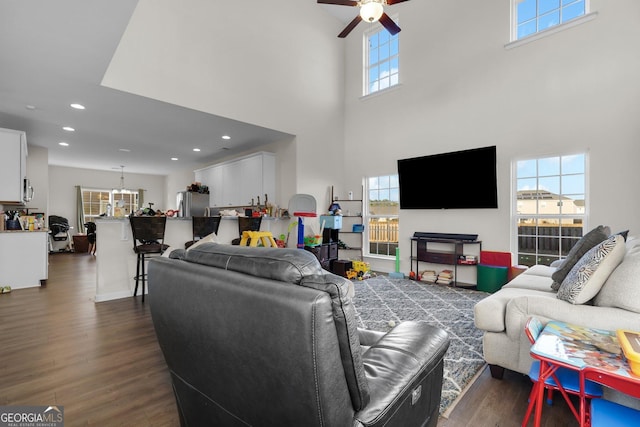 living room featuring ceiling fan, a high ceiling, and dark hardwood / wood-style flooring