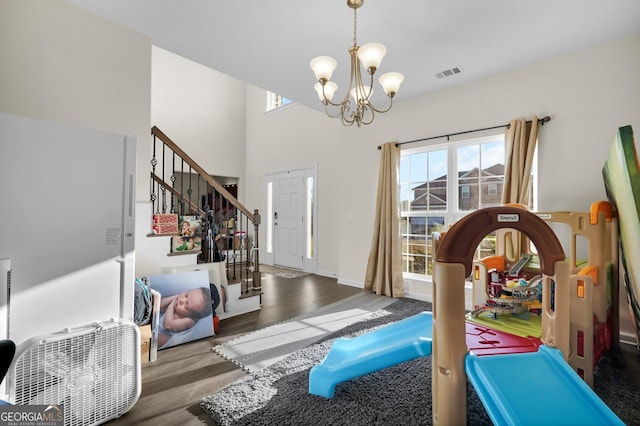 workout area with a healthy amount of sunlight, hardwood / wood-style flooring, a high ceiling, and a notable chandelier