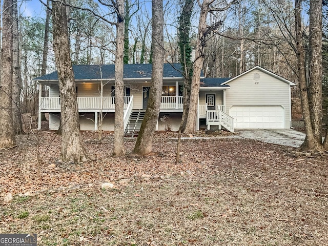 view of front of house with roof with shingles, covered porch, stairway, an attached garage, and driveway