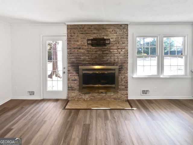 unfurnished living room with a fireplace, dark wood-type flooring, and crown molding