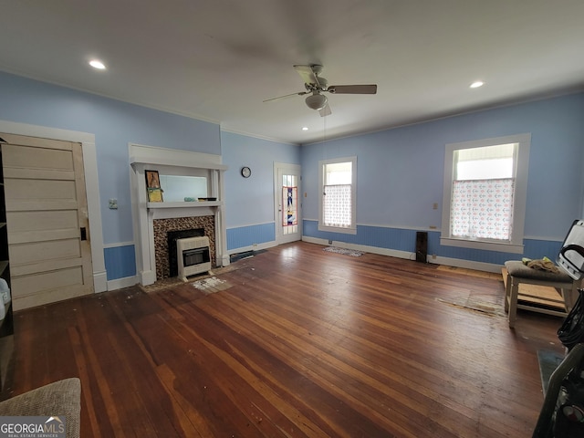 living room featuring a tiled fireplace, heating unit, ornamental molding, ceiling fan, and dark hardwood / wood-style floors