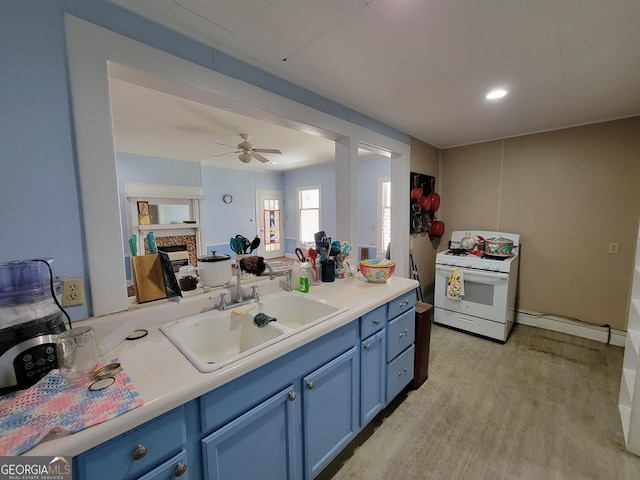 kitchen with a fireplace, light wood-type flooring, gas range gas stove, blue cabinets, and sink