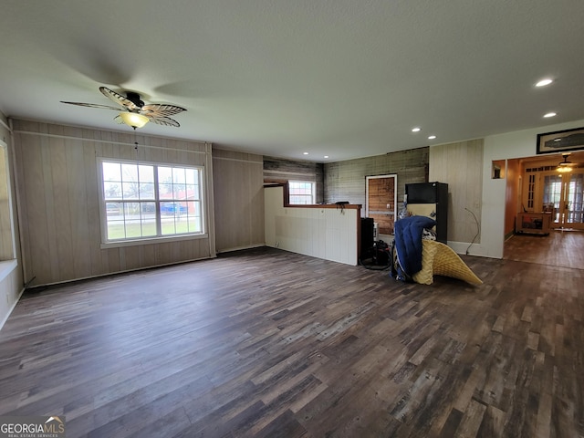 unfurnished living room featuring ceiling fan and dark wood-type flooring