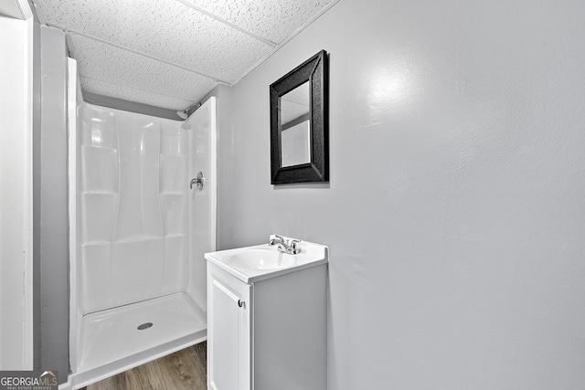 bathroom featuring a drop ceiling, vanity, wood-type flooring, and walk in shower