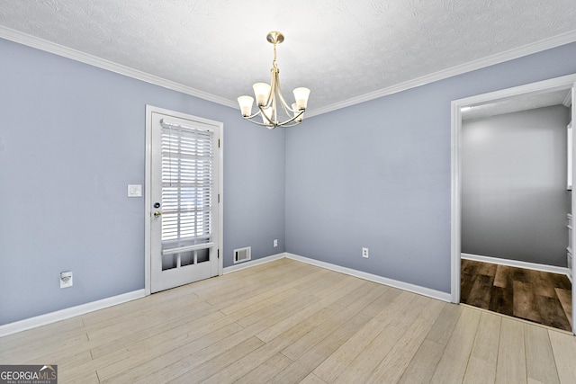 unfurnished room with a notable chandelier, ornamental molding, light wood-type flooring, and a textured ceiling