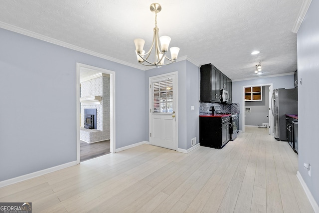 kitchen with light wood-type flooring, a brick fireplace, stainless steel appliances, backsplash, and crown molding