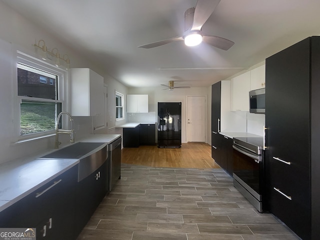 kitchen with appliances with stainless steel finishes, white cabinets, and ceiling fan