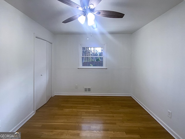 unfurnished bedroom with a closet, dark hardwood / wood-style floors, and ceiling fan