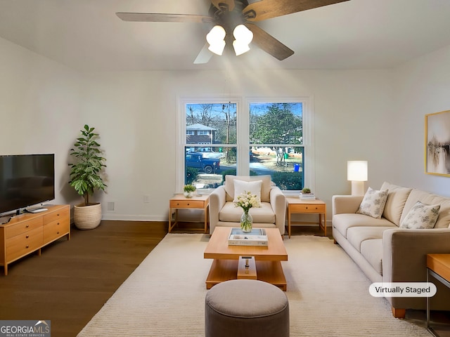 living room with a ceiling fan, baseboards, and wood finished floors