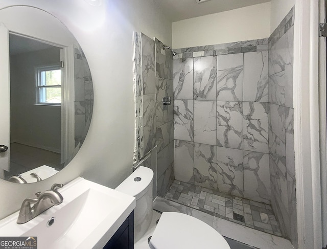 bathroom featuring vanity, a tile shower, and toilet