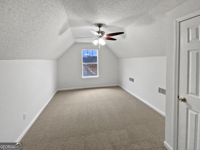 bonus room featuring baseboards, a ceiling fan, vaulted ceiling, a textured ceiling, and carpet flooring