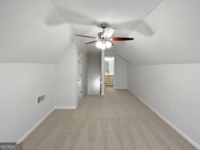 additional living space with visible vents, baseboards, vaulted ceiling, and a textured ceiling