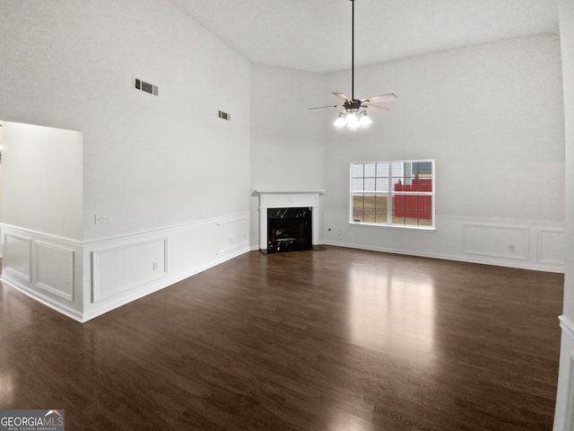 unfurnished living room featuring ceiling fan, visible vents, dark wood finished floors, and a high end fireplace