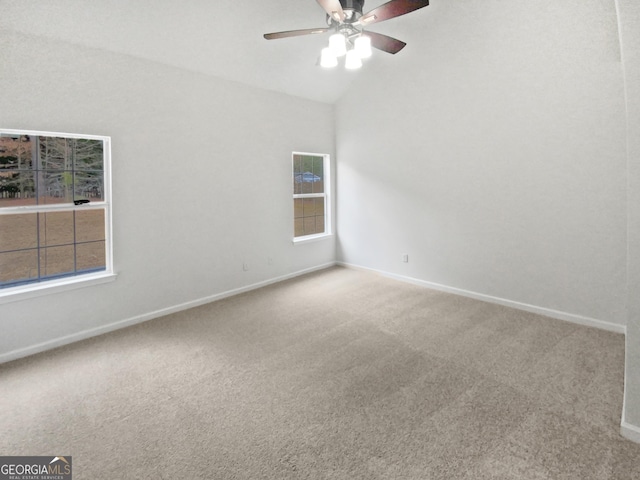 spare room featuring vaulted ceiling, carpet flooring, a ceiling fan, and baseboards