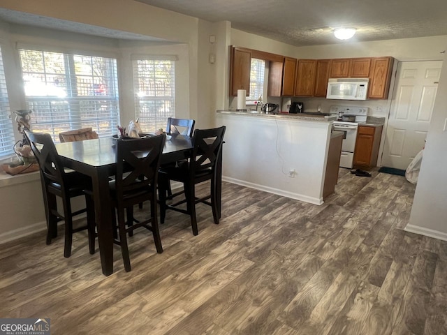 kitchen with kitchen peninsula, white appliances, and dark hardwood / wood-style flooring