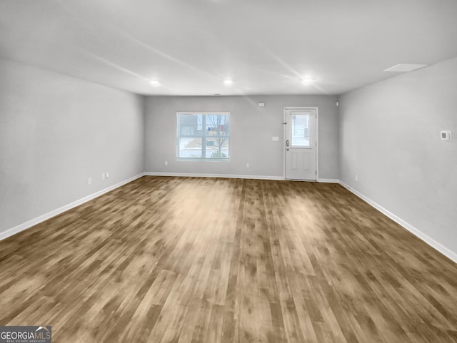 unfurnished living room with baseboards and wood finished floors