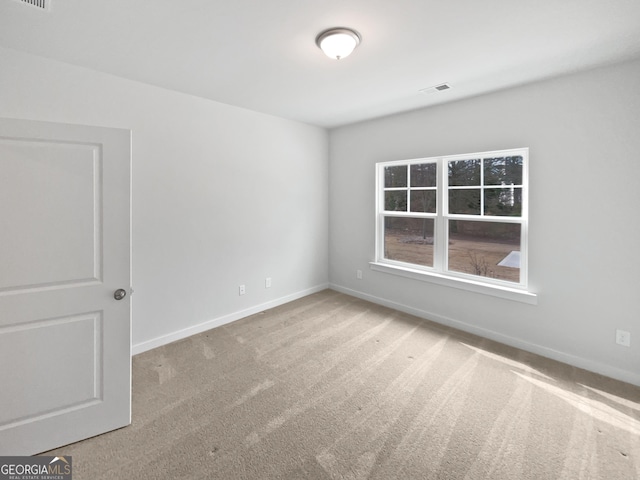 spare room with light carpet, visible vents, and baseboards