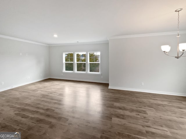 unfurnished room featuring dark hardwood / wood-style flooring, crown molding, and an inviting chandelier