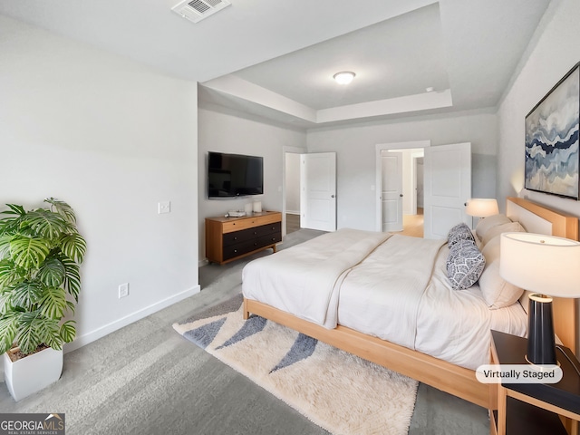 bedroom with carpet floors, a tray ceiling, visible vents, and baseboards