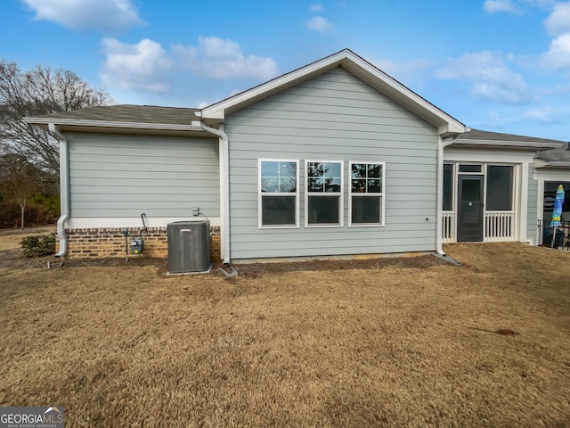 back of property featuring a shingled roof, a sunroom, a yard, and central AC unit