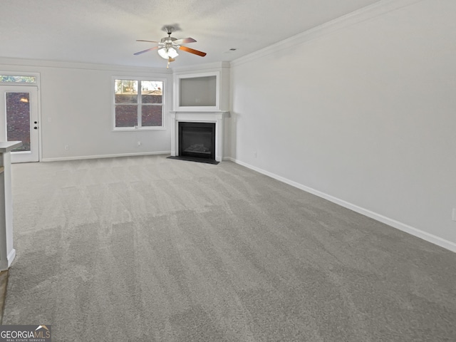 unfurnished living room featuring light colored carpet, a fireplace with flush hearth, ornamental molding, a ceiling fan, and baseboards