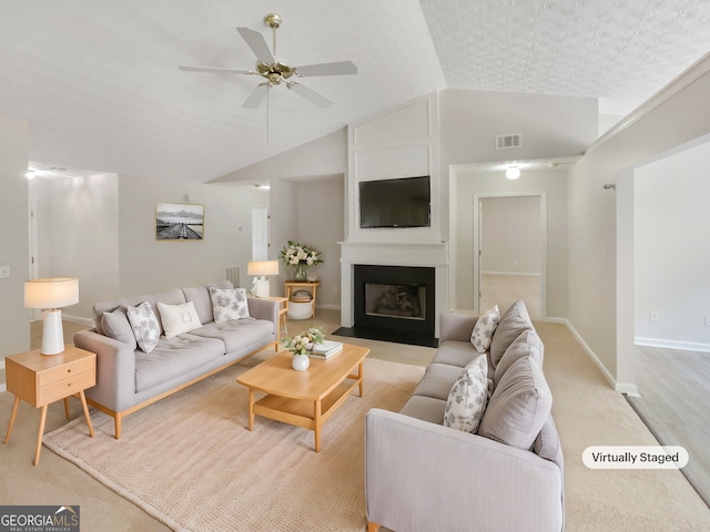 living room with light carpet, vaulted ceiling, ceiling fan, and a large fireplace