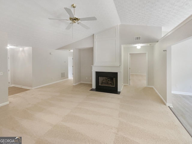 unfurnished living room featuring light carpet, lofted ceiling, ceiling fan, and a large fireplace