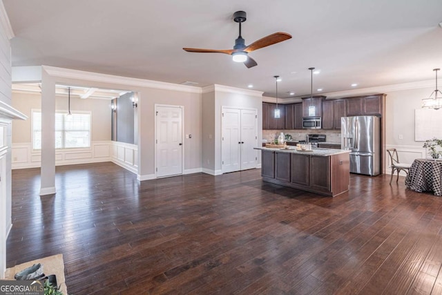 kitchen with dark brown cabinets, dark wood-type flooring, stainless steel appliances, an island with sink, and decorative light fixtures