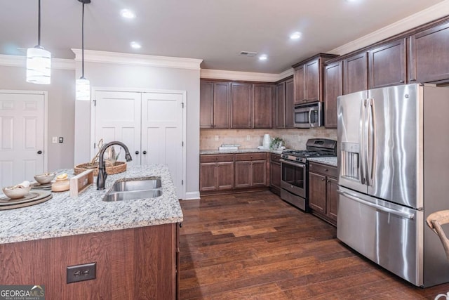 kitchen featuring stainless steel appliances, dark hardwood / wood-style flooring, sink, light stone counters, and pendant lighting