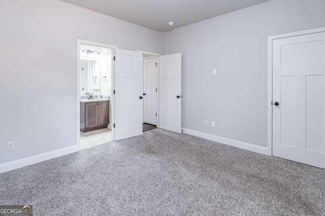 unfurnished bedroom with light carpet and connected bathroom