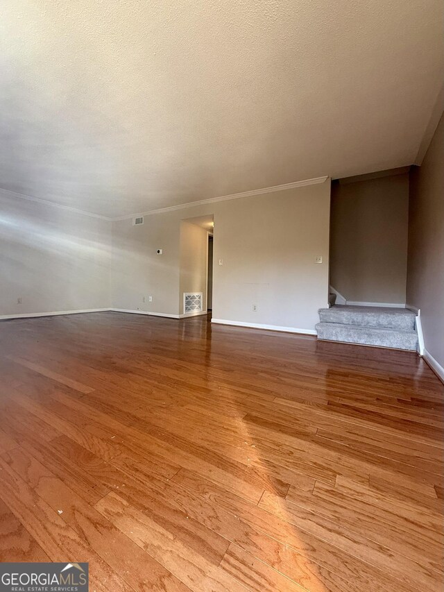 6900 Roswell Rd Unit 7N, Atlanta, GA 30328 - unfurnished living room with baseboards, visible vents, stairway, a textured ceiling, and light wood-type flooring