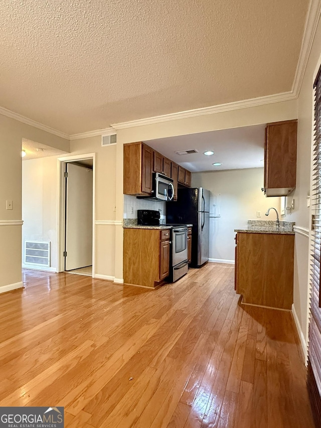 6900 Roswell Rd Unit 7N, Atlanta, GA 30328 - kitchen with appliances with stainless steel finishes, light wood-style floors, visible vents, and brown cabinets