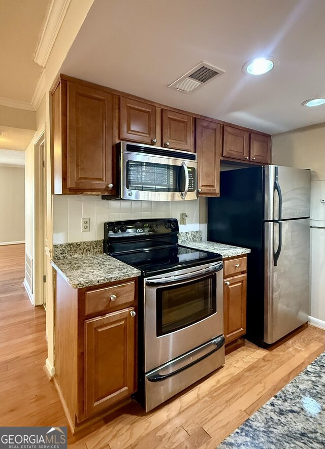 6900 Roswell Rd Unit 7N, Atlanta, GA 30328 - kitchen featuring stainless steel appliances, light wood finished floors, brown cabinetry, and visible vents