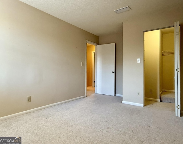 6900 Roswell Rd Unit 7N, Atlanta, GA 30328 - unfurnished bedroom with light colored carpet, visible vents, a spacious closet, a textured ceiling, and baseboards