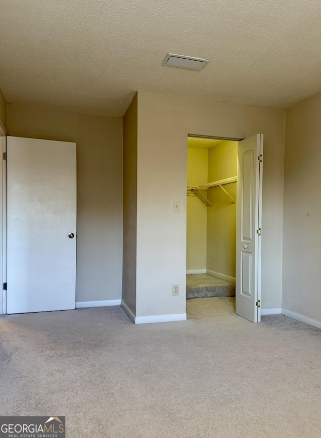 6900 Roswell Rd Unit 7N, Atlanta, GA 30328 - unfurnished bedroom featuring light carpet, a textured ceiling, and baseboards