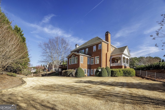 view of side of property featuring a chimney, fence, and brick siding