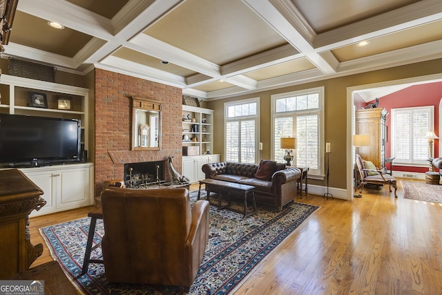 living area featuring light wood-style floors, a brick fireplace, plenty of natural light, and beamed ceiling