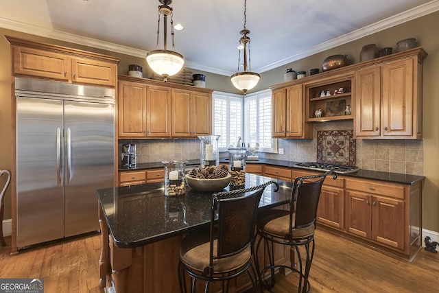 kitchen featuring stainless steel appliances, dark wood-type flooring, a kitchen island, brown cabinetry, and pendant lighting