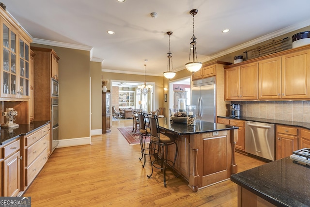 kitchen with a kitchen island, glass insert cabinets, a kitchen breakfast bar, built in appliances, and pendant lighting