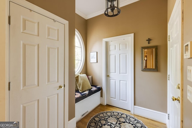 foyer with baseboards, crown molding, visible vents, and light wood finished floors