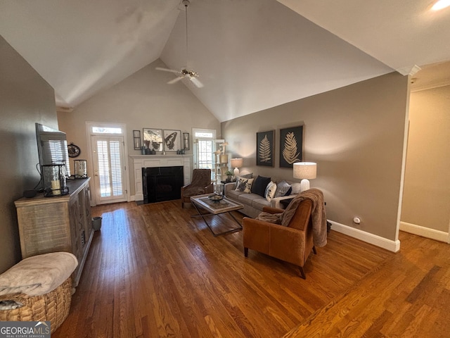 living room with dark wood-style floors, a fireplace, ceiling fan, high vaulted ceiling, and baseboards