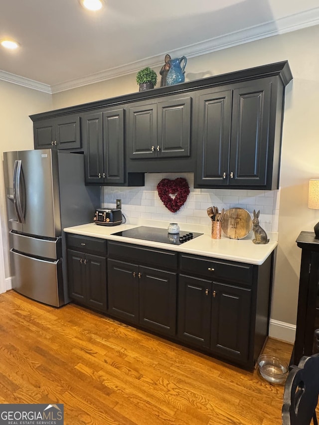 kitchen with stainless steel fridge, tasteful backsplash, black electric stovetop, crown molding, and light wood-type flooring