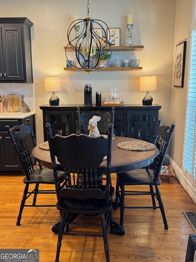 dining room with baseboards, visible vents, light wood-style flooring, and a notable chandelier