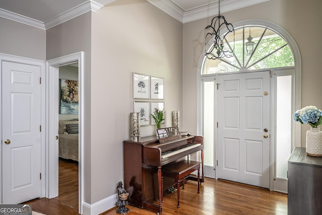 foyer entrance featuring baseboards, a chandelier, ornamental molding, and wood finished floors
