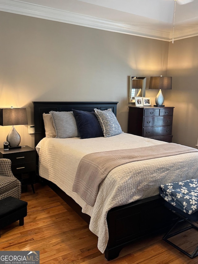 bedroom with ornamental molding and wood finished floors