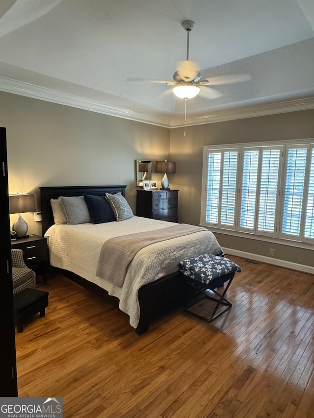 bedroom featuring ornamental molding, multiple windows, baseboards, and hardwood / wood-style flooring