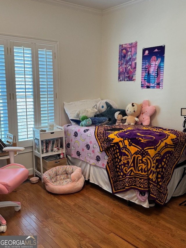 bedroom with crown molding and wood finished floors