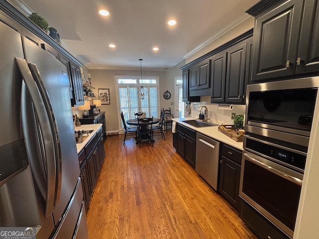 kitchen with crown molding, stainless steel appliances, a sink, and light countertops