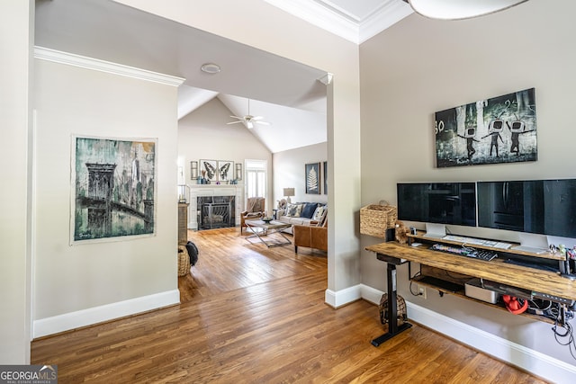 home office featuring crown molding, wood finished floors, a fireplace, baseboards, and a ceiling fan
