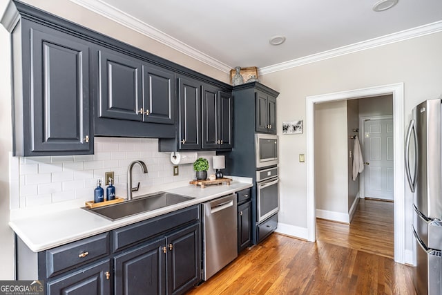 kitchen with decorative backsplash, crown molding, a sink, baseboards, and stainless steel appliances